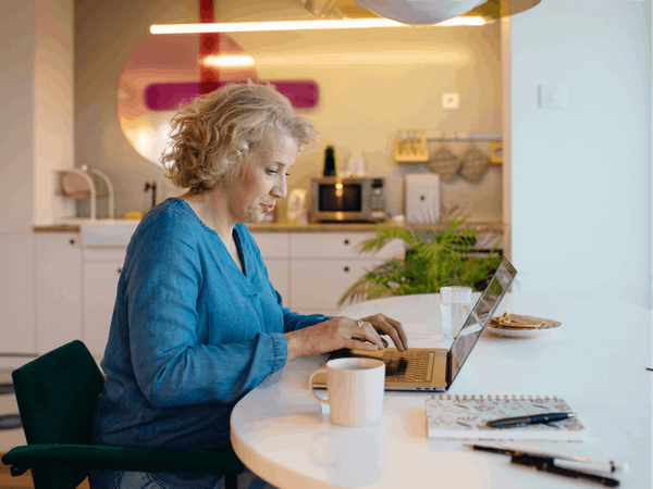 A women is sat at a desk, typing on her laptop.