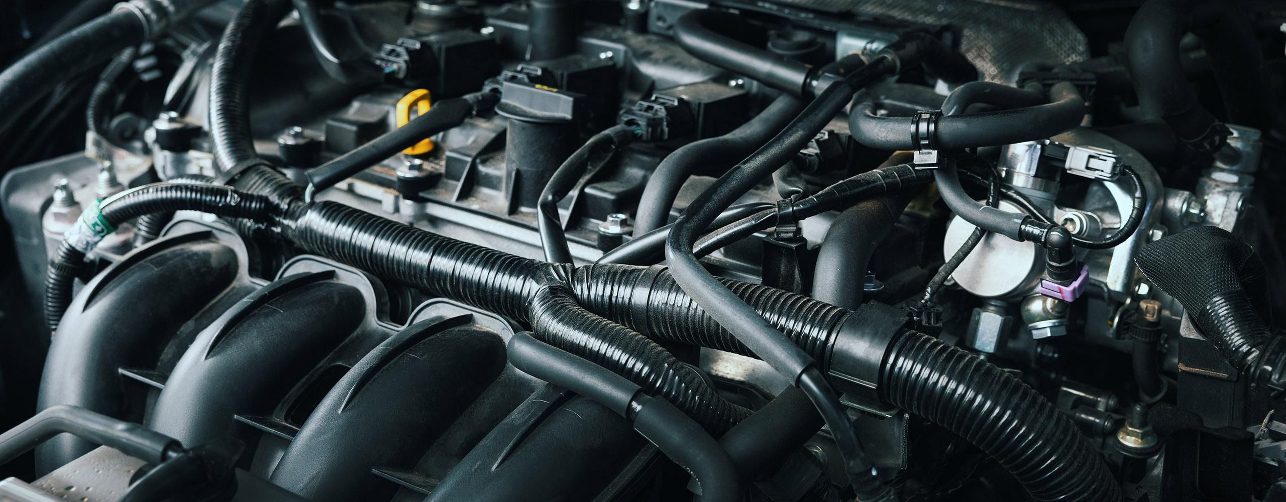 Ein Bildausschnitt der Oberseite eines Automotors aus überwiegend schwarzen Motorteilen.
