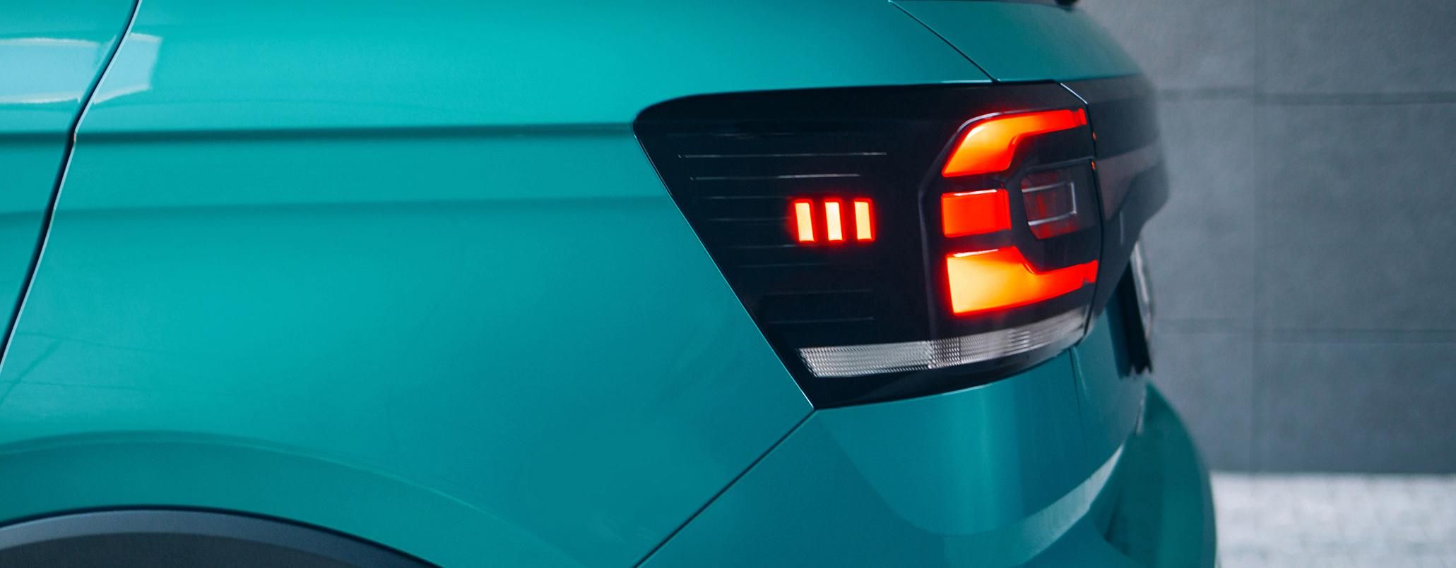 Rückansicht eines türkisen Fahrzeugs, bei dem der rechte Blinker aufleuchtet.