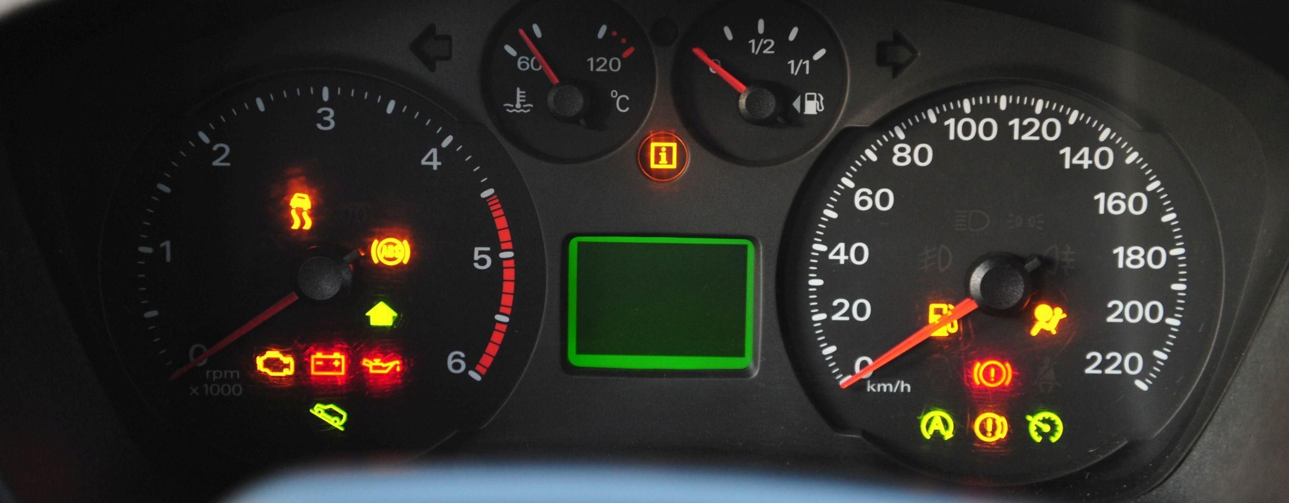 Das Cockpit eines startenden Autos. Die Motorkontrollleuchte ist ganz links unten zu finden und leuchtet orange