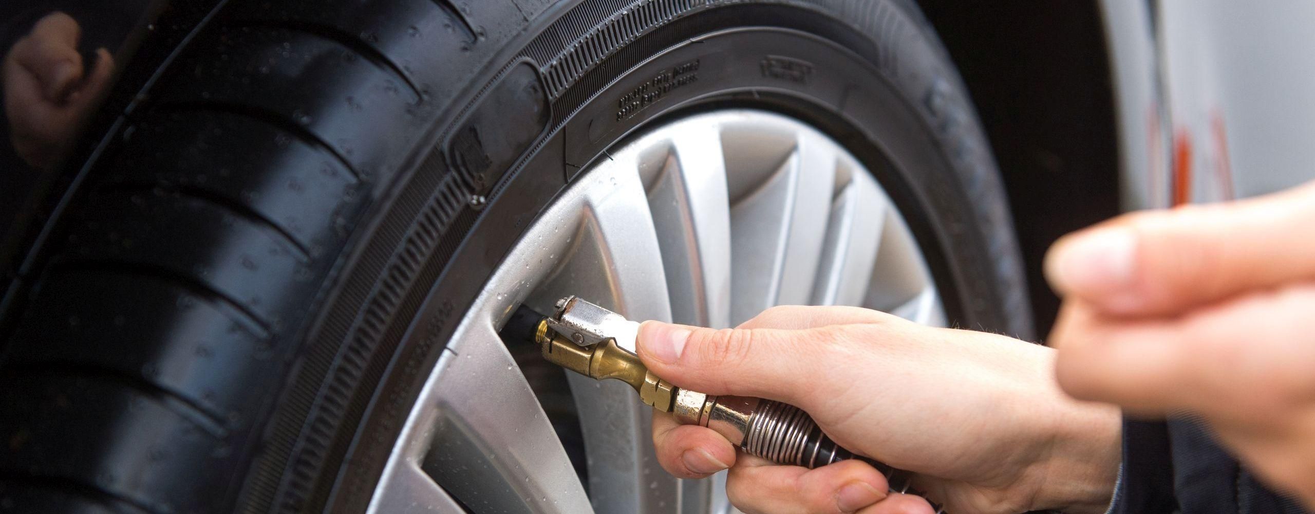 Eine Person prüft den Reifendruck am Auto