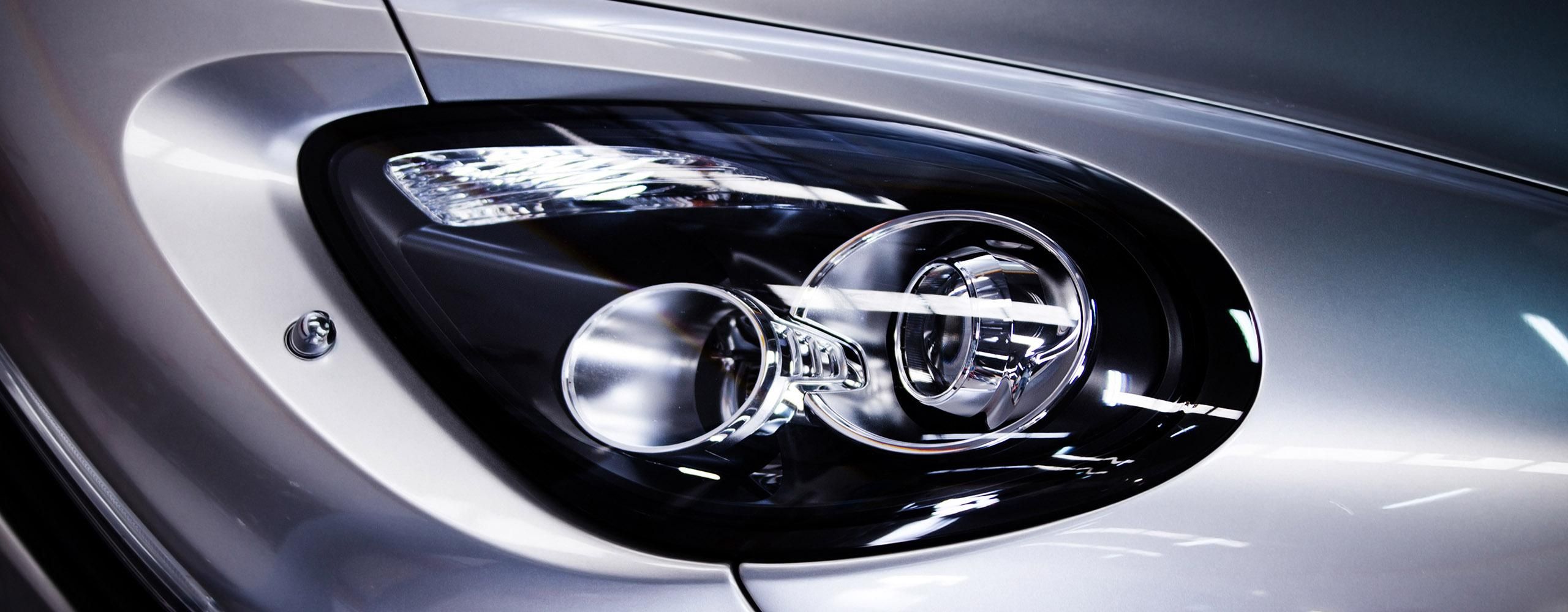 Der Bi-Xenon-Scheinwerfer eines silbernen Autos am Tag