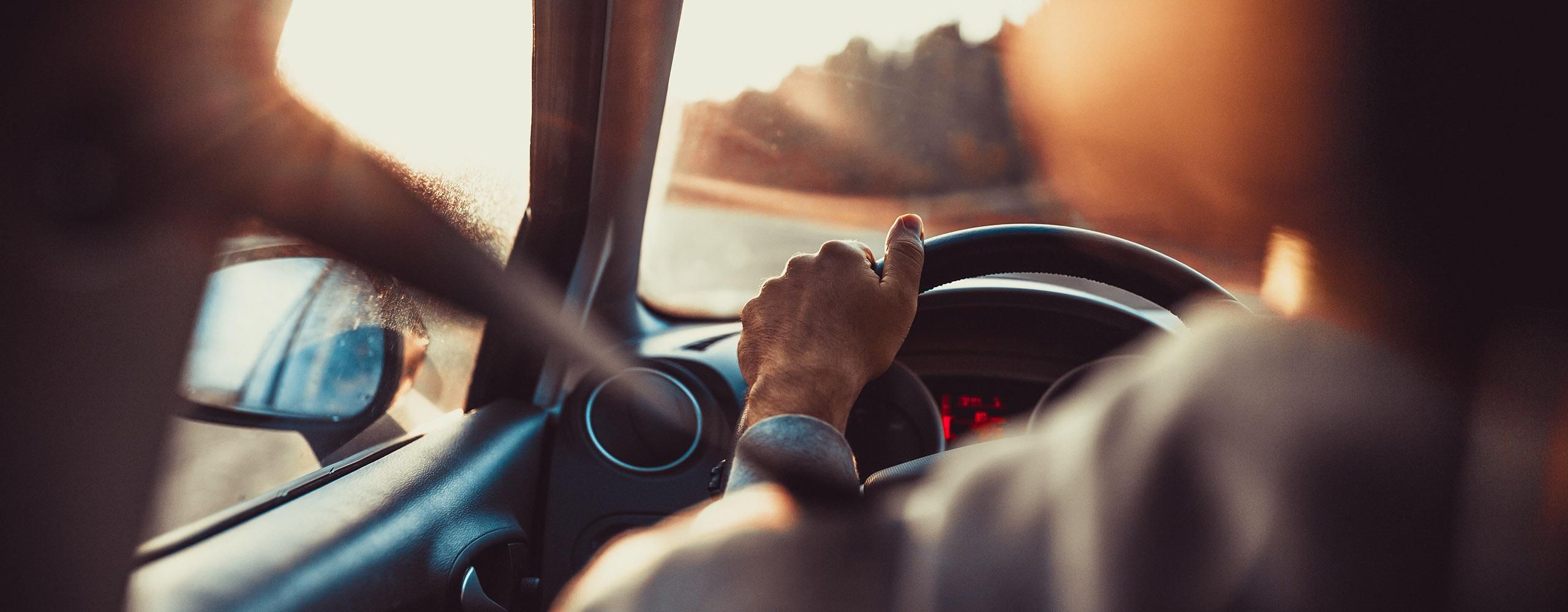 Blick von hinten links im Inneren eines Autos über die Schulter der Person am Steuer