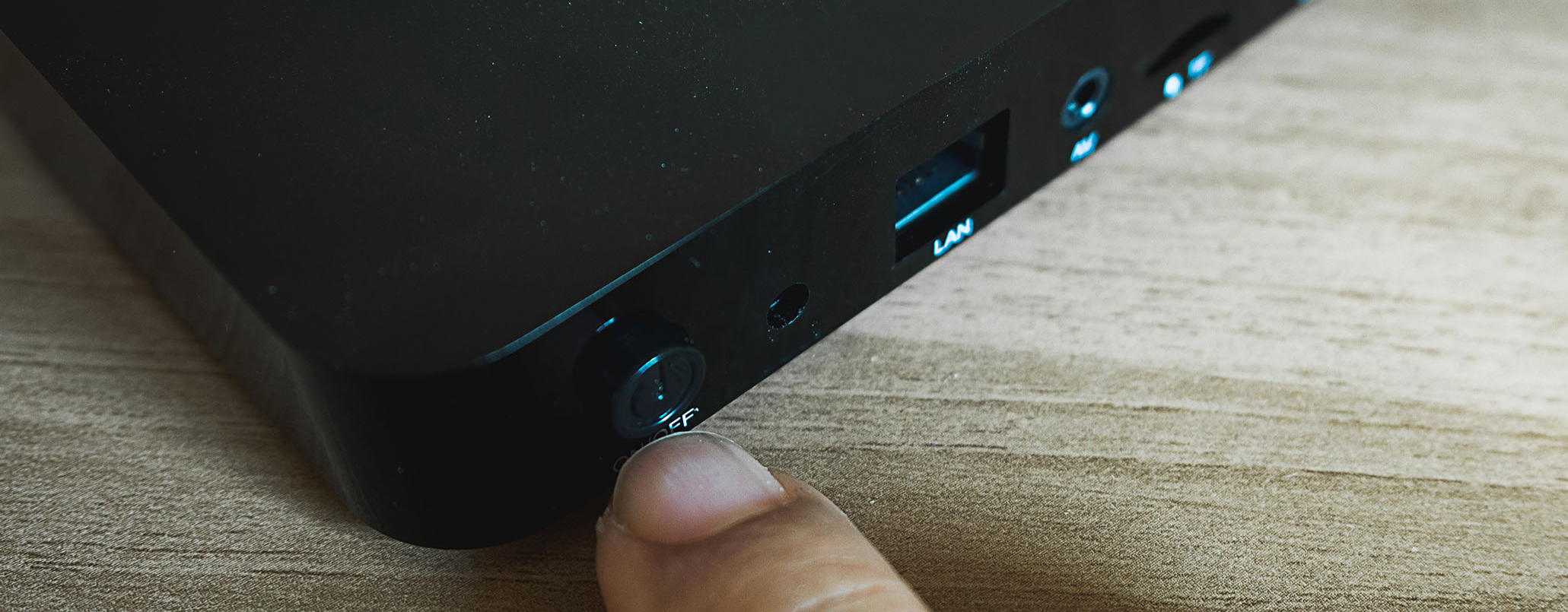 Ein Finger drückt auf einen Knopf an einem WiFi-Router.