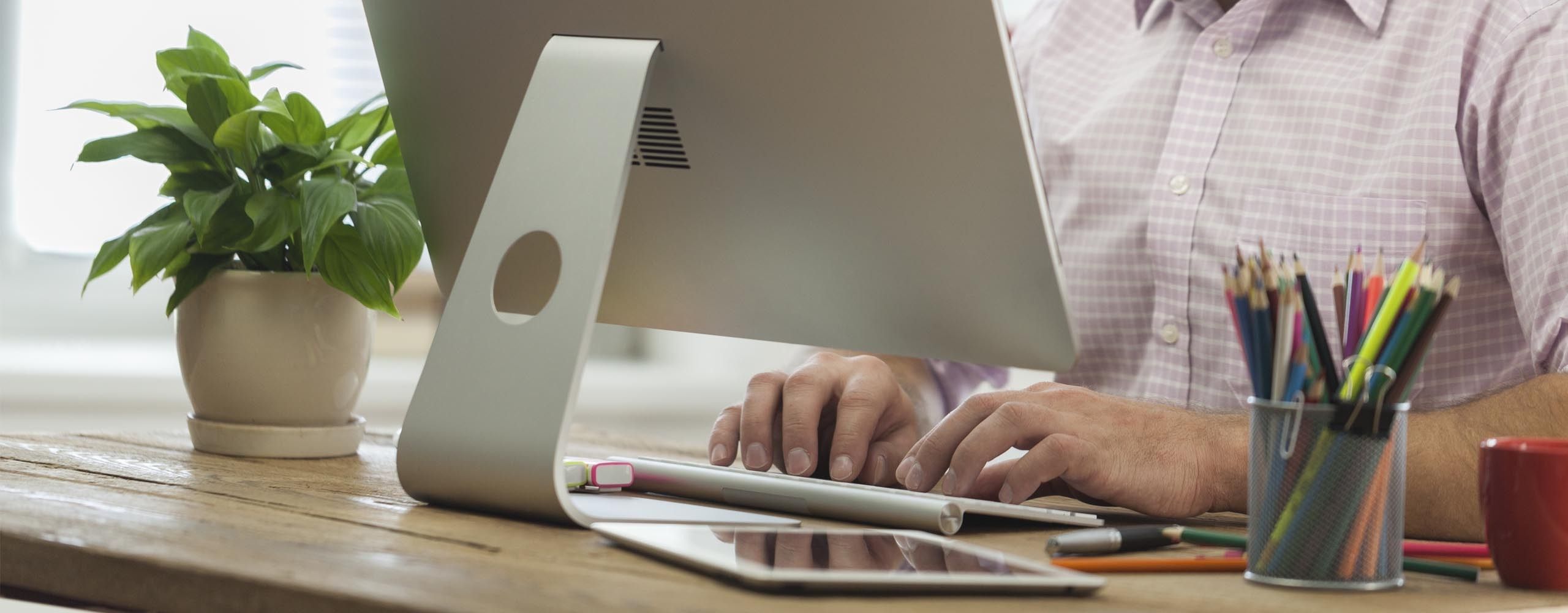 Ein Mann sitzt am Schreibtisch vor einem Computerbildschirm.