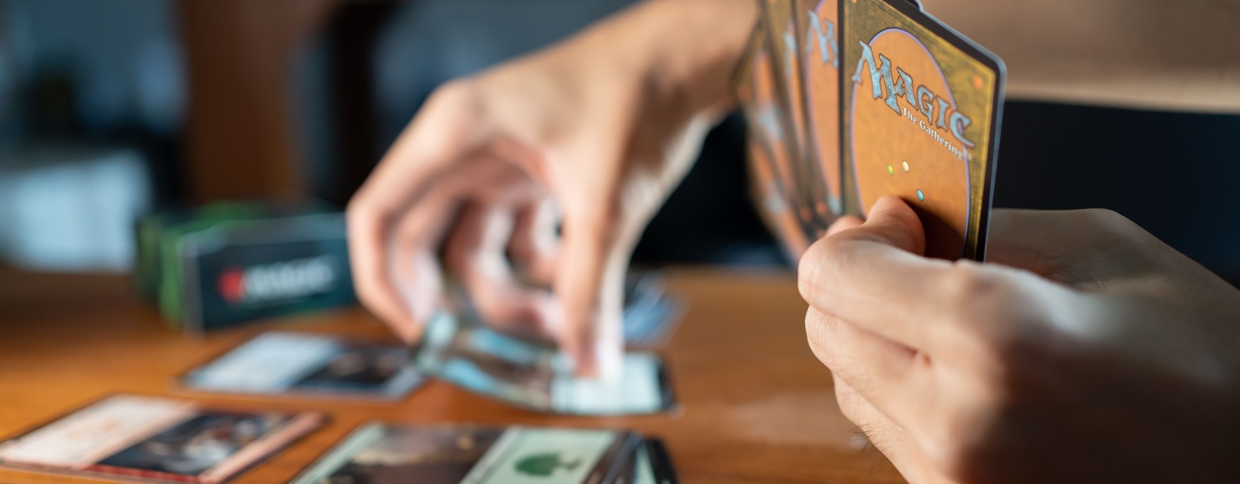 Eine Hand ragt in den linken Bildrand und greift nach Spielkarten.