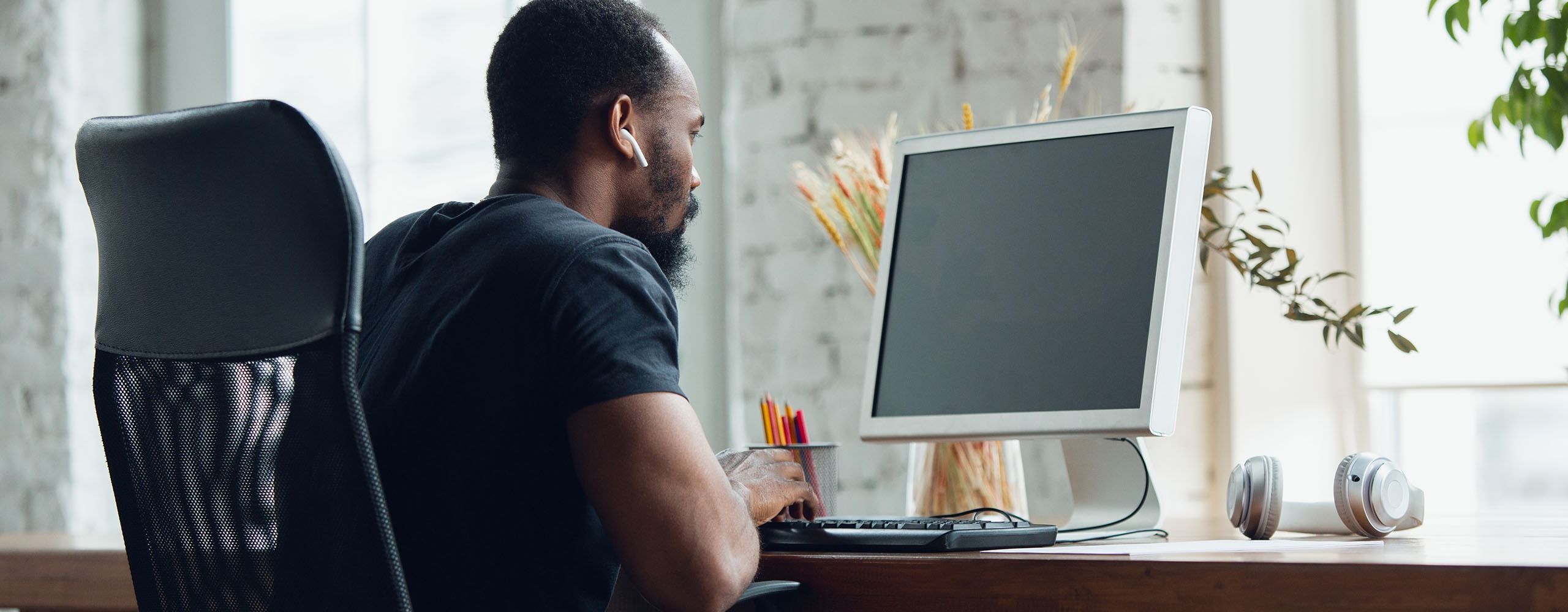 Ein Mann sitzt an einem Schreibtisch und der Monitor vor ihm hat kein Signal.